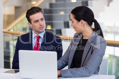 Business executives discussing over laptop
