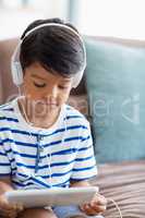 Boy listening music on digital tablet in living room