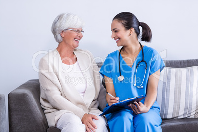 Doctor and senior woman discussing on clipboard