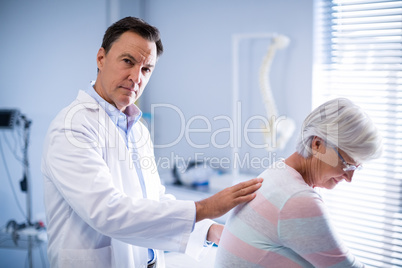 Portrait of physiotherapist giving back massage to senior patient