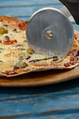 Delicious pizza served on pizza tray with cutter on pizza