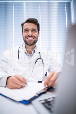 Male doctor writing on clipboard