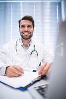 Male doctor writing on clipboard