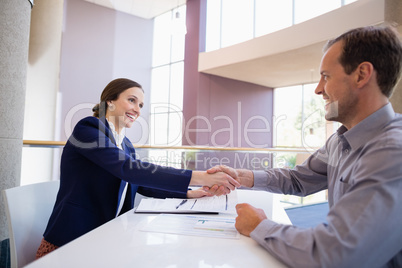 Businesswoman shaking hands with colleague at desk