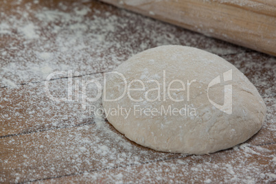 Rolling pin with pizza dough and flour on rolling board