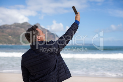 Mature man taking a selfie from mobile phone on the beach