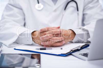 Mid section of doctor sitting at desk