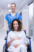 Portrait of doctor pushing a pregnant woman on wheelchair