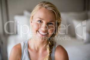 Smiling beautiful woman sitting on bed in bedroom