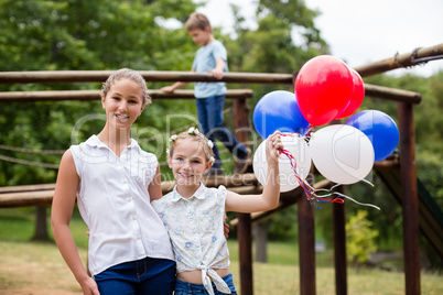 Two girls smiling while holding balloons in park