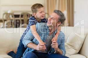 Smiling son embracing a father in living room