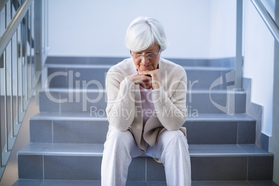 Upset senior woman sitting on stairs