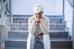 Upset senior woman sitting on stairs