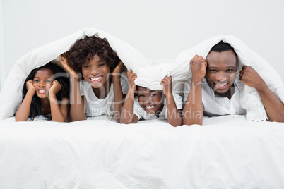 Portrait of parents and kids lying on bed