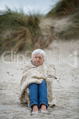 Senior woman wrapped in shawl on the beach