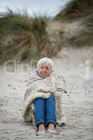 Senior woman wrapped in shawl on the beach