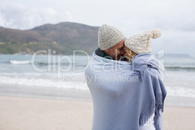 Mature couple wrapped in blanket on the beach