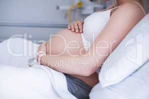 Mid section pregnant woman relaxing on hospital bed