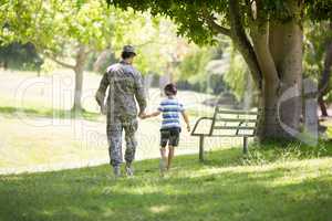 Army soldier walking with boy in park