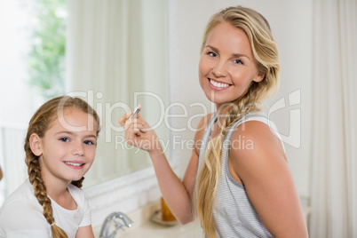 Smiling mother and daughter standing in bathroom