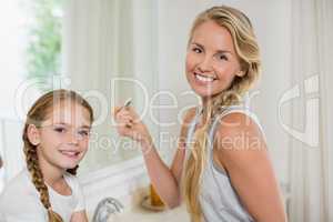 Smiling mother and daughter standing in bathroom