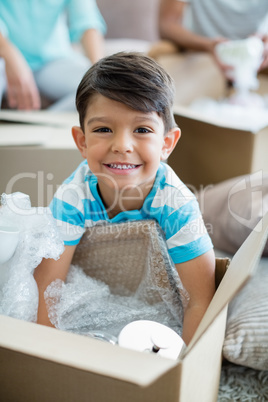 Boy unpacking carton boxes in living room at new home