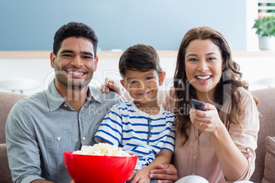 Parents and son watching television in living room