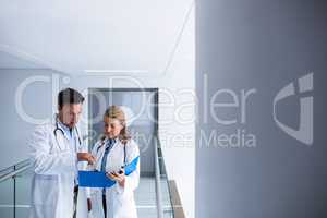 Male and female doctor discussing over a report in the passageway