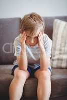 Portrait of upset boy sitting on sofa in corridor