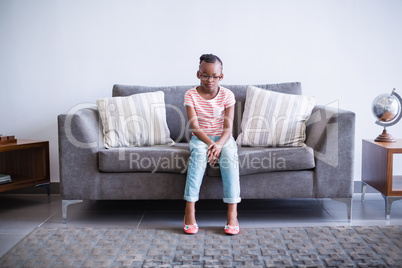 Upset girl sitting on sofa in corridor