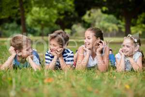Happy children interacting with each other while lying on grass