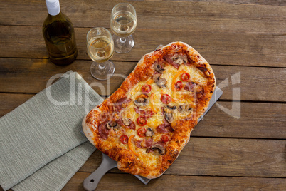 Delicious pizza served on pizza tray with a glasses of wine bottle and wine