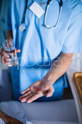 Doctor serving medicine to female senior patient on bed