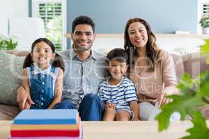 Portrait of happy parents and kids sitting on sofa in living room