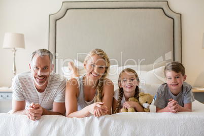 Parents with their kids lying on bed in bedroom