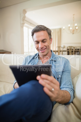 Man sitting on sofa and using digital tablet in living room