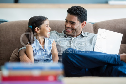 Father and daughter interacting on sofa in living room