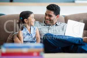 Father and daughter interacting on sofa in living room