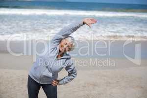 Senior woman doing stretching exercise on the beach