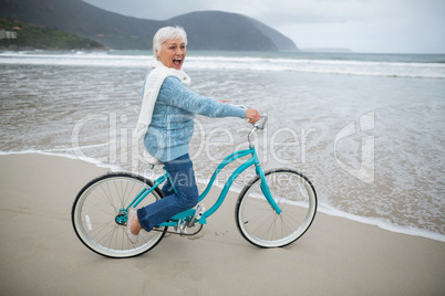 Senior woman riding bicycle on the beach