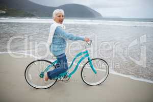 Senior woman riding bicycle on the beach