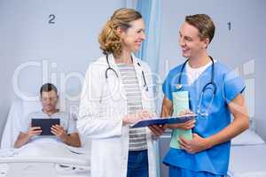 Doctors examining reports and patient using digital tablet in background