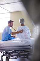 Male doctor examining senior female patient with a stethoscope