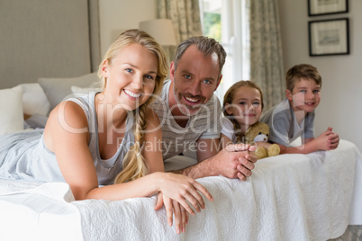 Parents with their kids lying on bed in bedroom