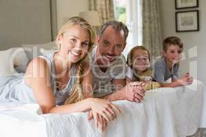 Parents with their kids lying on bed in bedroom