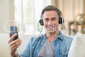 Man listening to music on headphones in living room at home
