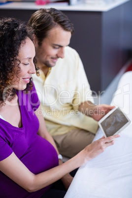 Couple looking at babies ultrasound scan on digital tablet