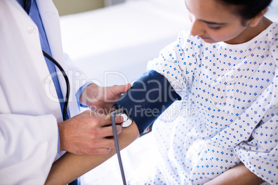 Male doctor checking blood pressure of female patient