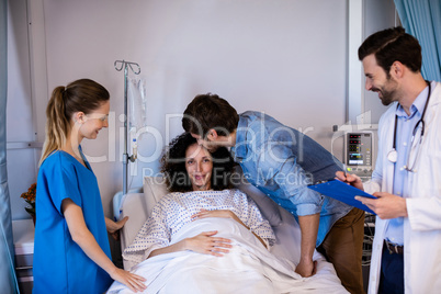 Man kissing pregnant woman on her forehead in the ward