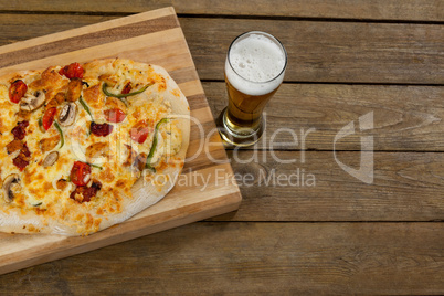 Delicious pizza served on pizza tray with a glass of beer on wooden plank